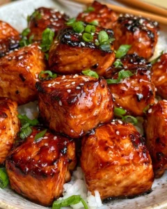 Crispy honey garlic salmon bites served on a plate garnished with herbs